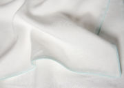 Detail of galets duvet cover with pale green piping on natural wh