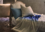 Ombré blue and white thorw with 2 pillows on a bed